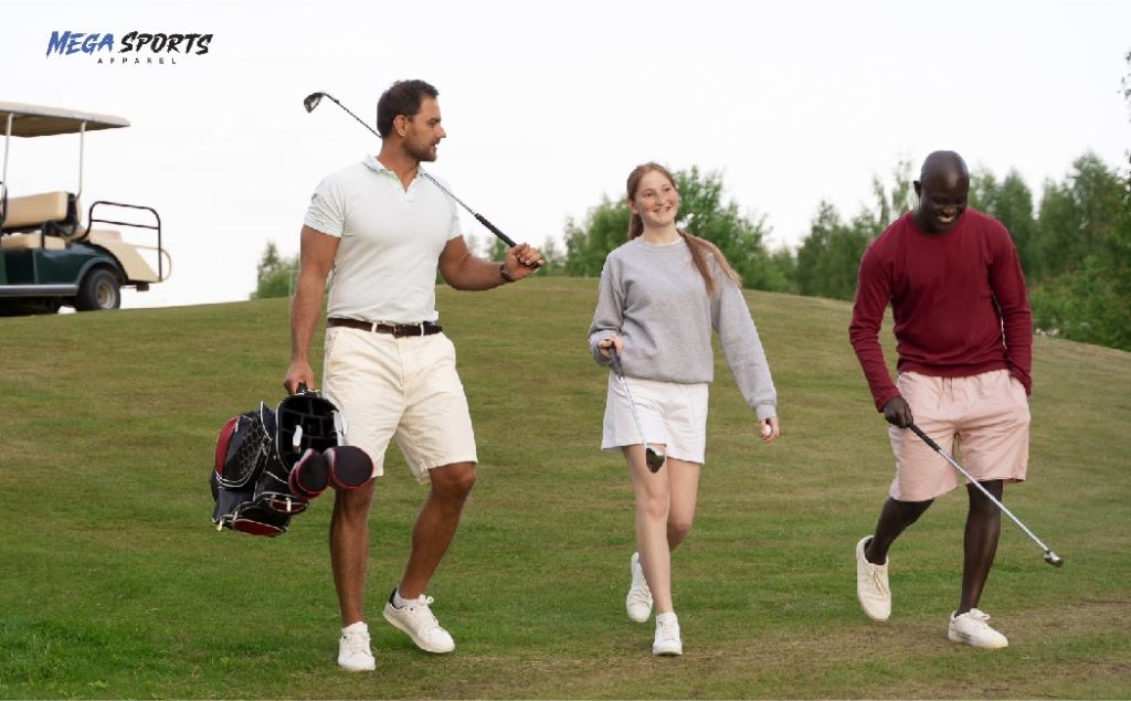 Three golfers wearing golf clothes walk on a grassy course with trees and a cart in the background