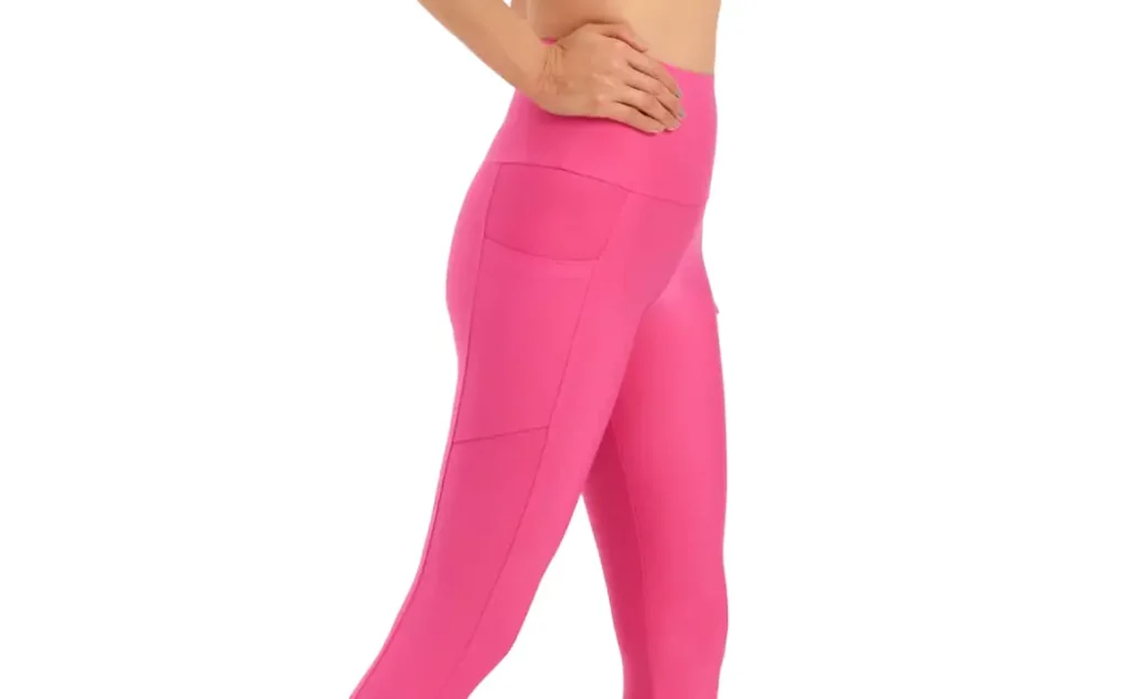 A woman wearing a pair of pink midcalf leggings with pockets on the side